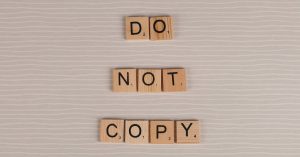 Close-up of wooden tiles spelling 'Do Not Copy' on a textured surface.