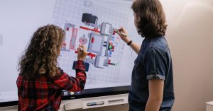 Two children engaging with a smart board in a modern classroom setting.